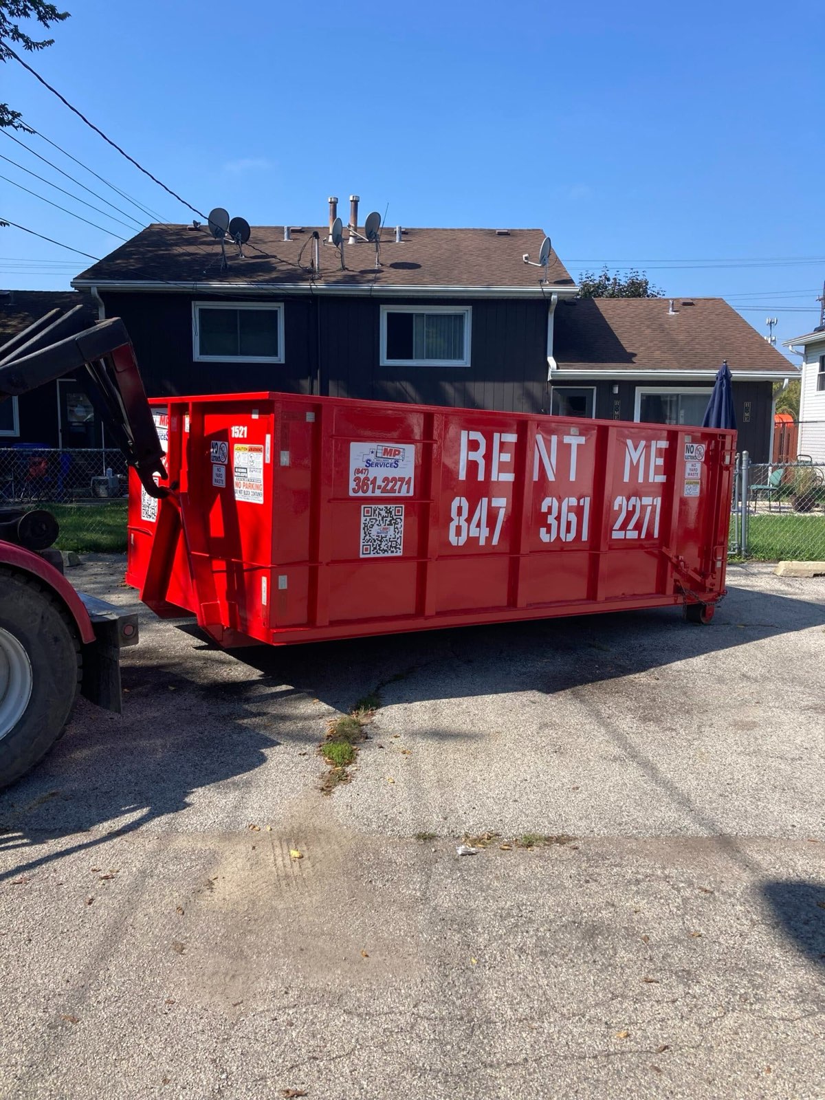 Red roll off dumpster loaded onto an MP Roll Off Services truck