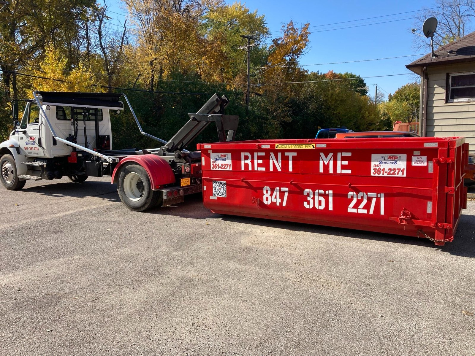 MP Roll Off Services truck delivering a dumpster to a jobsite